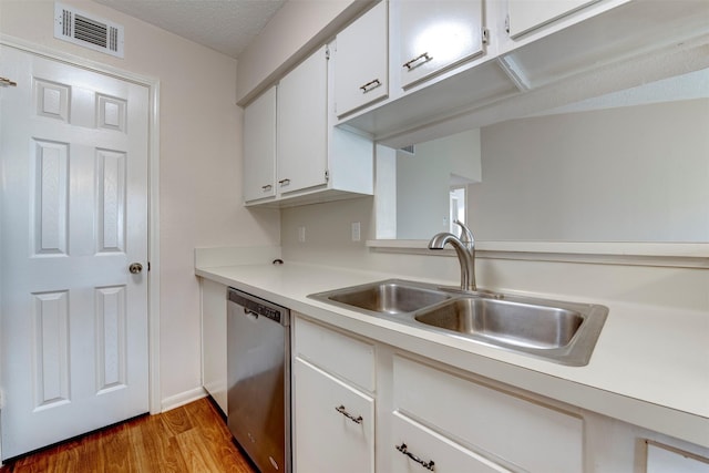 kitchen with sink, hardwood / wood-style floors, a textured ceiling, white cabinets, and stainless steel dishwasher