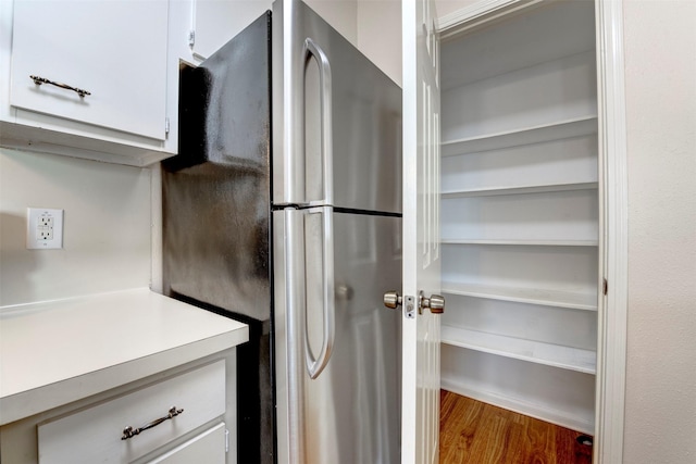 kitchen with white cabinets, hardwood / wood-style floors, and stainless steel fridge