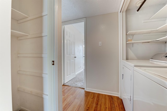 laundry area with a textured ceiling, independent washer and dryer, and light hardwood / wood-style floors