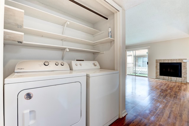 washroom with dark hardwood / wood-style flooring, a tiled fireplace, washer and clothes dryer, and a textured ceiling