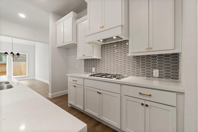 kitchen with pendant lighting, dark wood-type flooring, stainless steel gas stovetop, and white cabinets