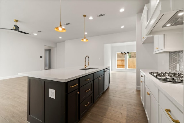 kitchen with white cabinetry, an island with sink, decorative light fixtures, and sink