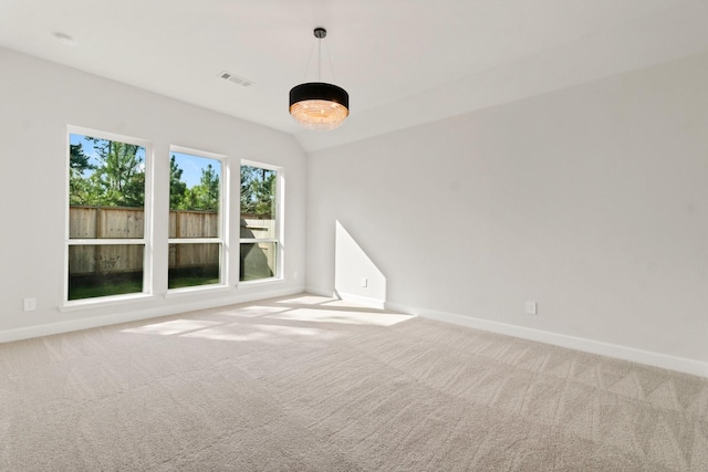 carpeted spare room with vaulted ceiling