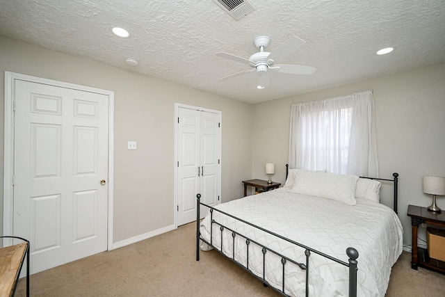 bedroom featuring ceiling fan, light colored carpet, and a textured ceiling