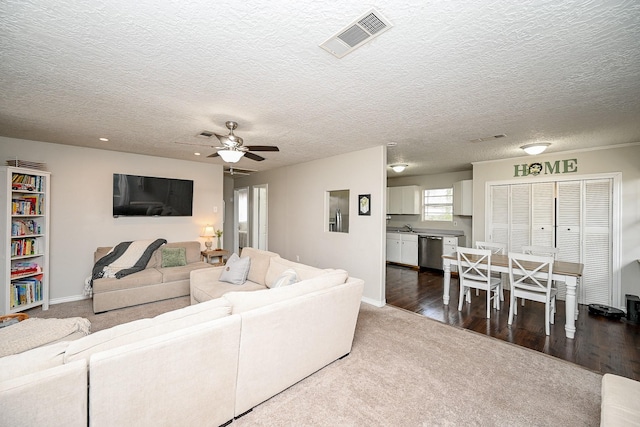 living room featuring dark hardwood / wood-style floors, sink, a textured ceiling, and ceiling fan