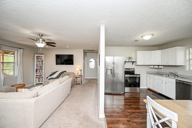 kitchen with sink, dark wood-type flooring, ceiling fan, appliances with stainless steel finishes, and white cabinetry