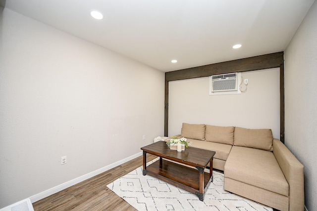 living room featuring a wall mounted air conditioner and light hardwood / wood-style floors