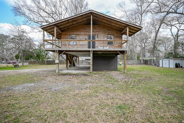 back of house featuring a wooden deck, a lawn, and a storage unit