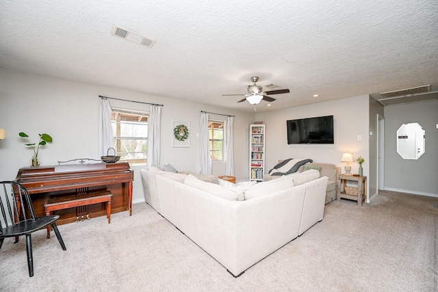 carpeted living room featuring ceiling fan and a textured ceiling