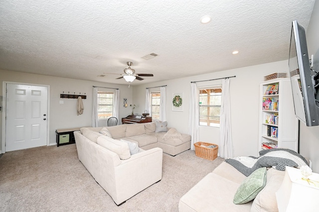 living room with a textured ceiling, a wealth of natural light, light colored carpet, and ceiling fan