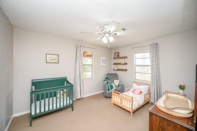 carpeted bedroom featuring multiple windows, a textured ceiling, and ceiling fan