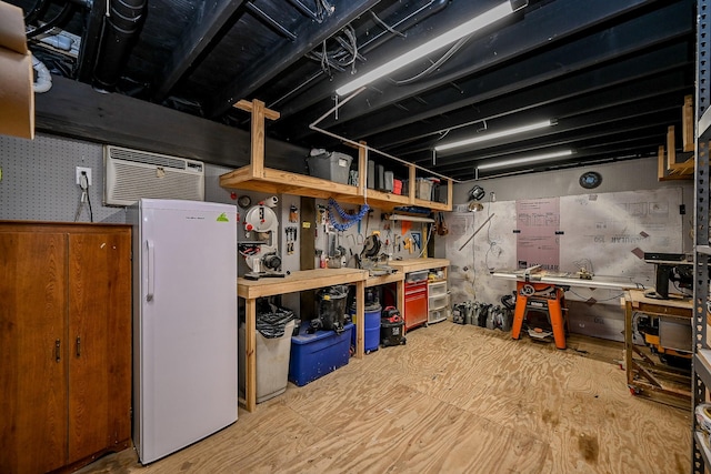 basement with a wall mounted AC, refrigerator, and a workshop area