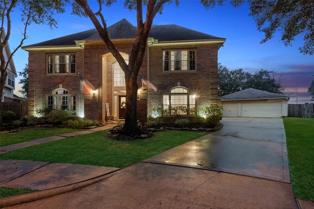 view of front facade with a yard, brick siding, a detached garage, and an outdoor structure