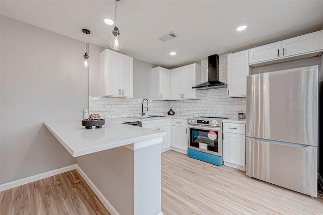 kitchen featuring visible vents, a sink, a peninsula, appliances with stainless steel finishes, and wall chimney exhaust hood