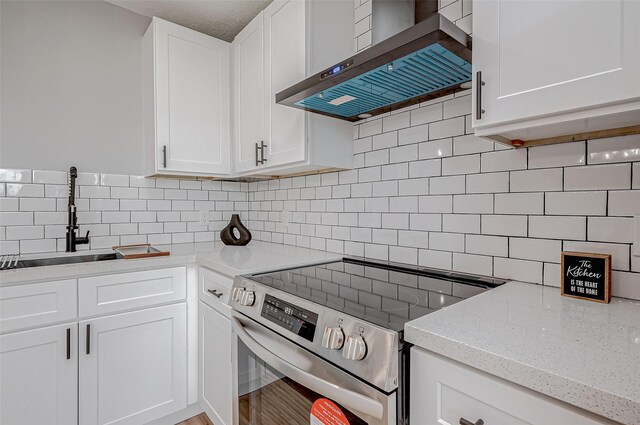 kitchen with white cabinets, stainless steel range with electric stovetop, backsplash, and wall chimney range hood