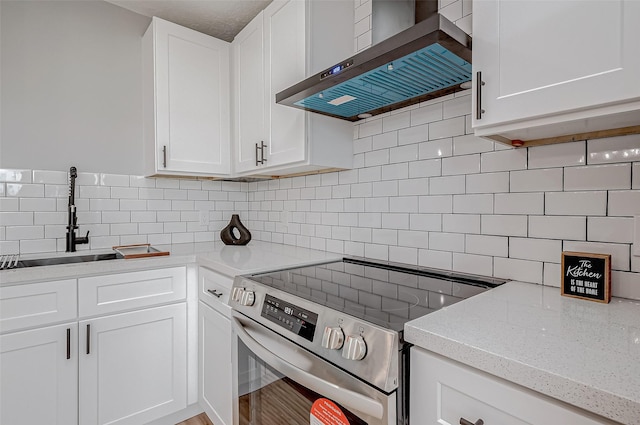 kitchen with stainless steel electric stove, wall chimney exhaust hood, and tasteful backsplash