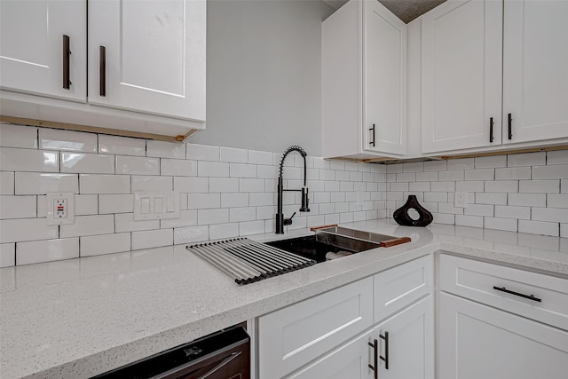 kitchen featuring white cabinets, backsplash, and a sink