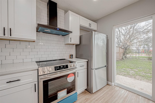 kitchen featuring tasteful backsplash, stainless steel appliances, wall chimney exhaust hood, and light countertops