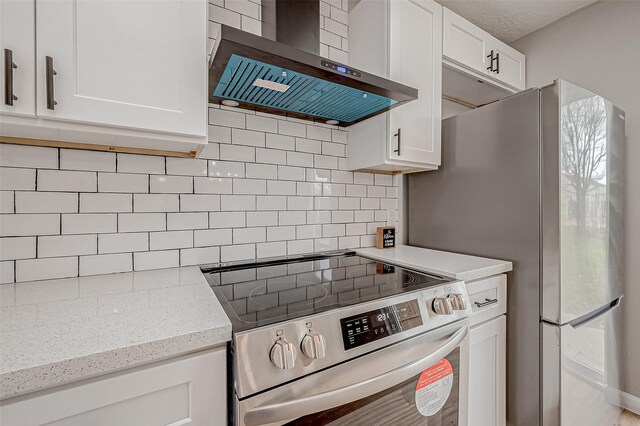 kitchen with tasteful backsplash, appliances with stainless steel finishes, wall chimney exhaust hood, and white cabinetry