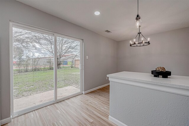 unfurnished dining area with a chandelier and light hardwood / wood-style floors