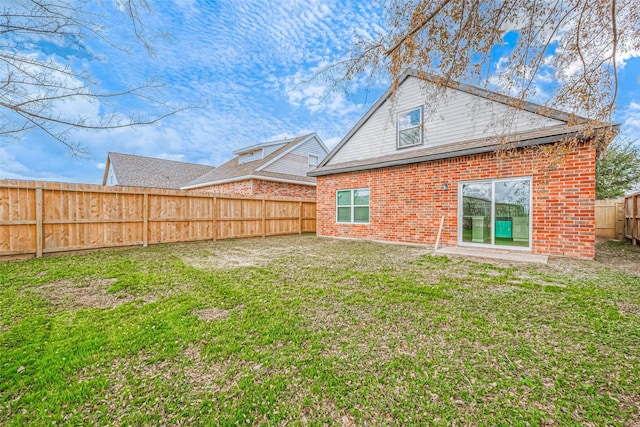 back of property featuring brick siding, a fenced backyard, and a lawn