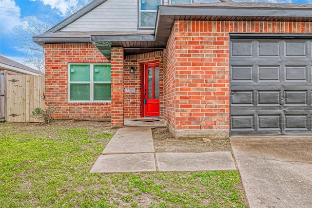 exterior space with brick siding, an attached garage, and fence