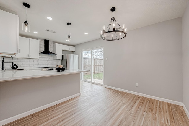 kitchen with visible vents, a sink, backsplash, appliances with stainless steel finishes, and wall chimney range hood