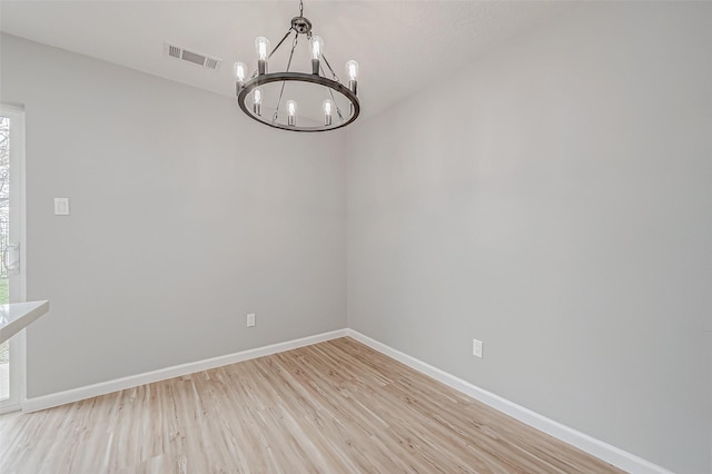 unfurnished dining area featuring an inviting chandelier and light hardwood / wood-style flooring