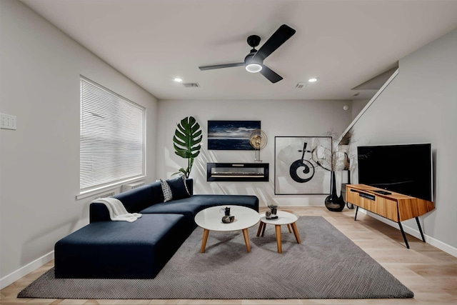 living area with a ceiling fan, wood finished floors, visible vents, baseboards, and recessed lighting