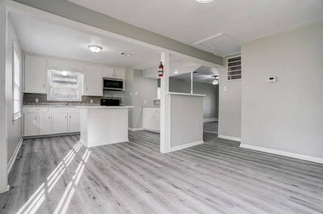 kitchen featuring white cabinets, backsplash, and light hardwood / wood-style flooring