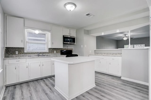 kitchen with white cabinetry, a center island, black electric range oven, and sink