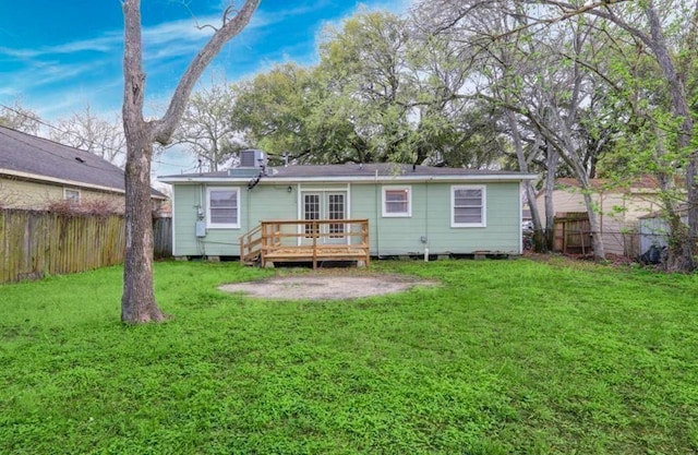 rear view of property featuring a wooden deck, a lawn, and french doors