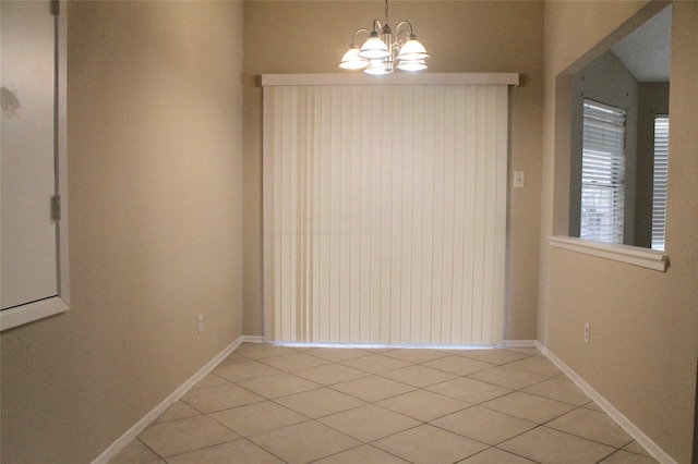 spare room featuring light tile patterned floors and a notable chandelier