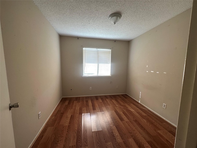 spare room featuring dark hardwood / wood-style floors and a textured ceiling