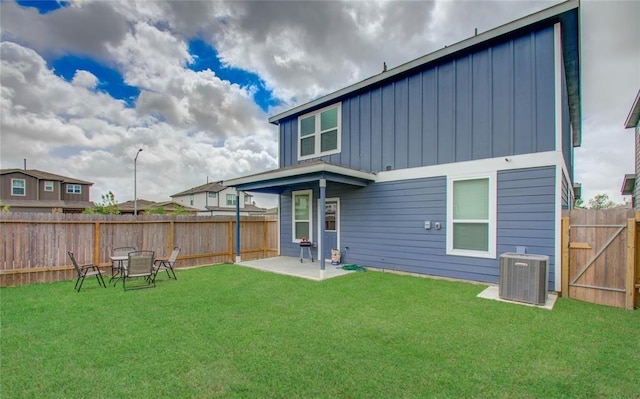 rear view of house with cooling unit, a yard, and a patio area