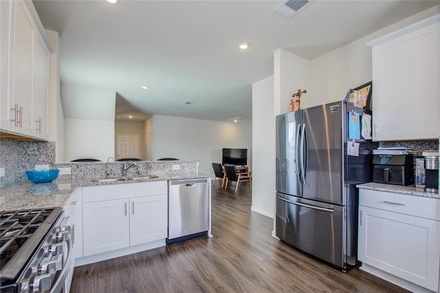 kitchen with sink, stainless steel appliances, dark hardwood / wood-style floors, light stone countertops, and white cabinets