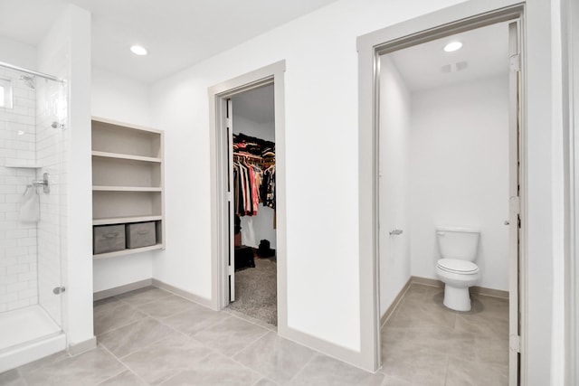 bathroom with tile patterned floors, toilet, and a shower with shower door