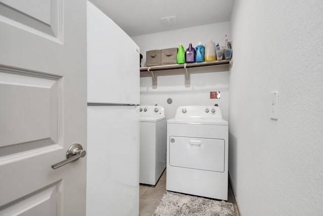 washroom with light tile patterned floors and washer and clothes dryer