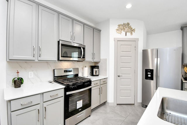 kitchen with light tile patterned floors, sink, gray cabinets, appliances with stainless steel finishes, and backsplash