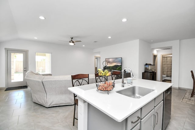 kitchen with sink, gray cabinets, a breakfast bar area, dishwasher, and an island with sink