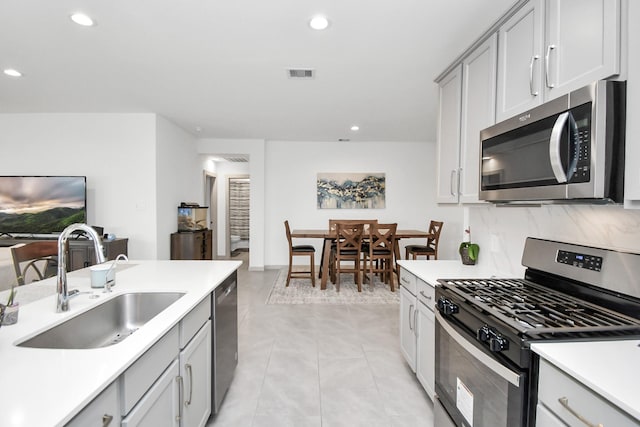 kitchen featuring gray cabinets, appliances with stainless steel finishes, sink, decorative backsplash, and light tile patterned floors