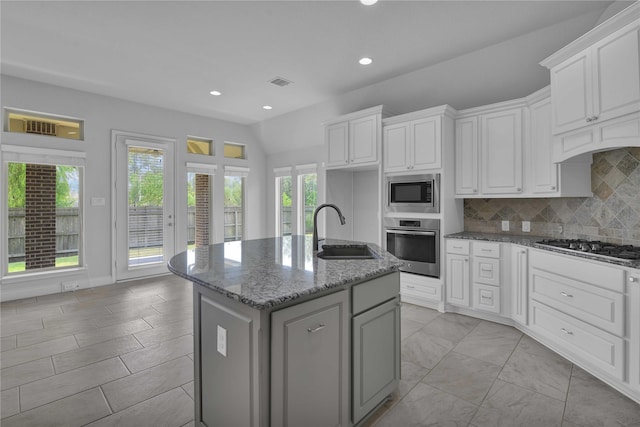 kitchen with sink, a center island with sink, stainless steel appliances, light stone countertops, and white cabinets