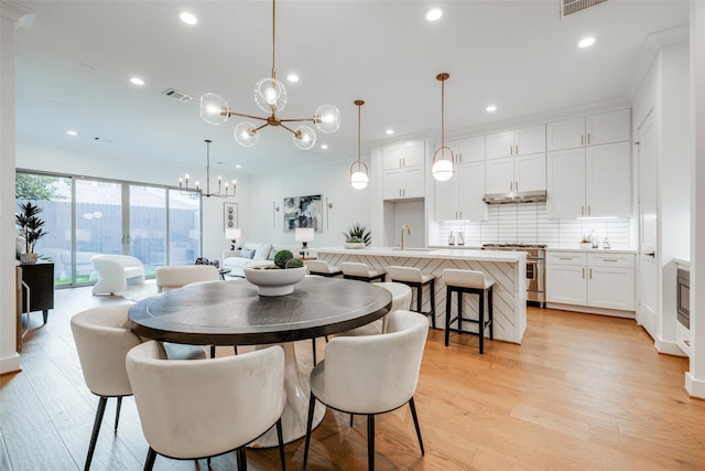 dining space with sink, a notable chandelier, and light wood-type flooring