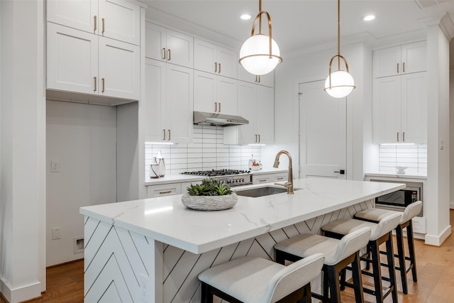 kitchen featuring white cabinetry, a center island with sink, and decorative light fixtures