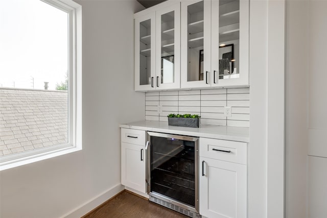 bar featuring dark hardwood / wood-style flooring, decorative backsplash, beverage cooler, and white cabinets