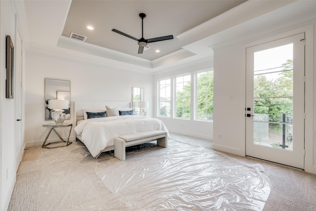 carpeted bedroom with a tray ceiling, ornamental molding, and ceiling fan