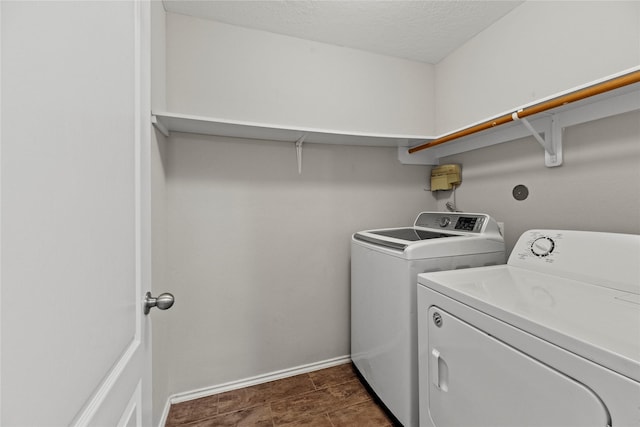 washroom featuring laundry area, baseboards, separate washer and dryer, and a textured ceiling