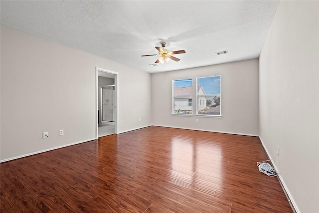 spare room with a ceiling fan, visible vents, a textured ceiling, and wood finished floors