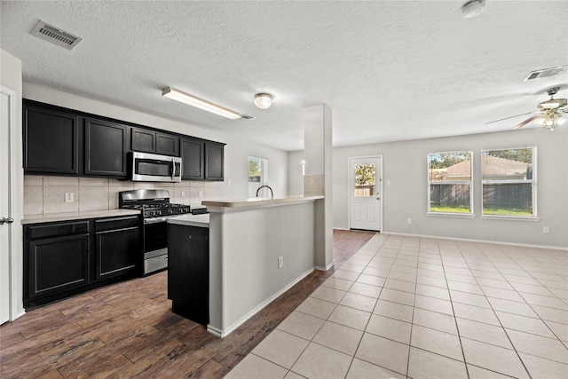 kitchen featuring tasteful backsplash, sink, ceiling fan, light hardwood / wood-style floors, and stainless steel appliances