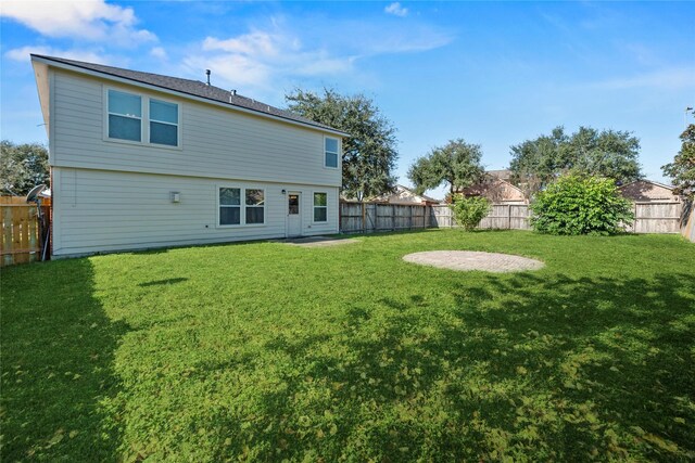 rear view of property featuring a fenced backyard and a yard